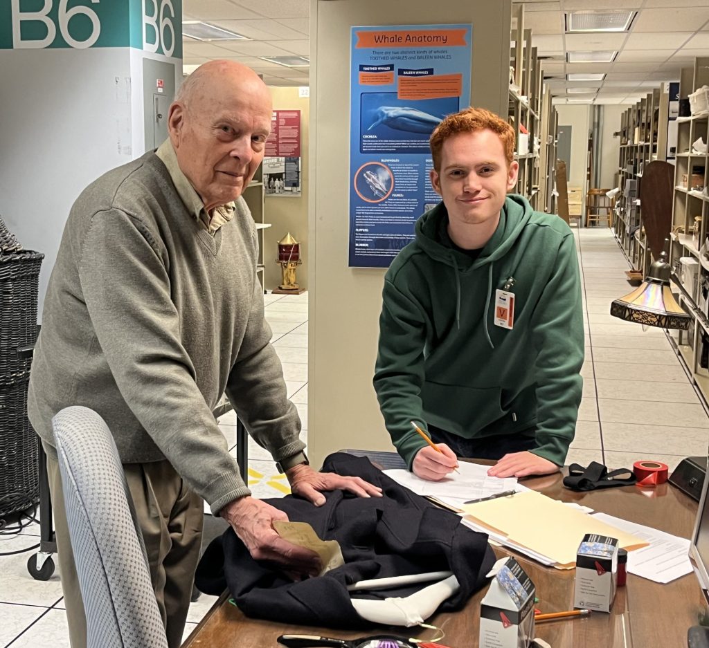 Two volunteers catalogue a uniform in the collections storage space.